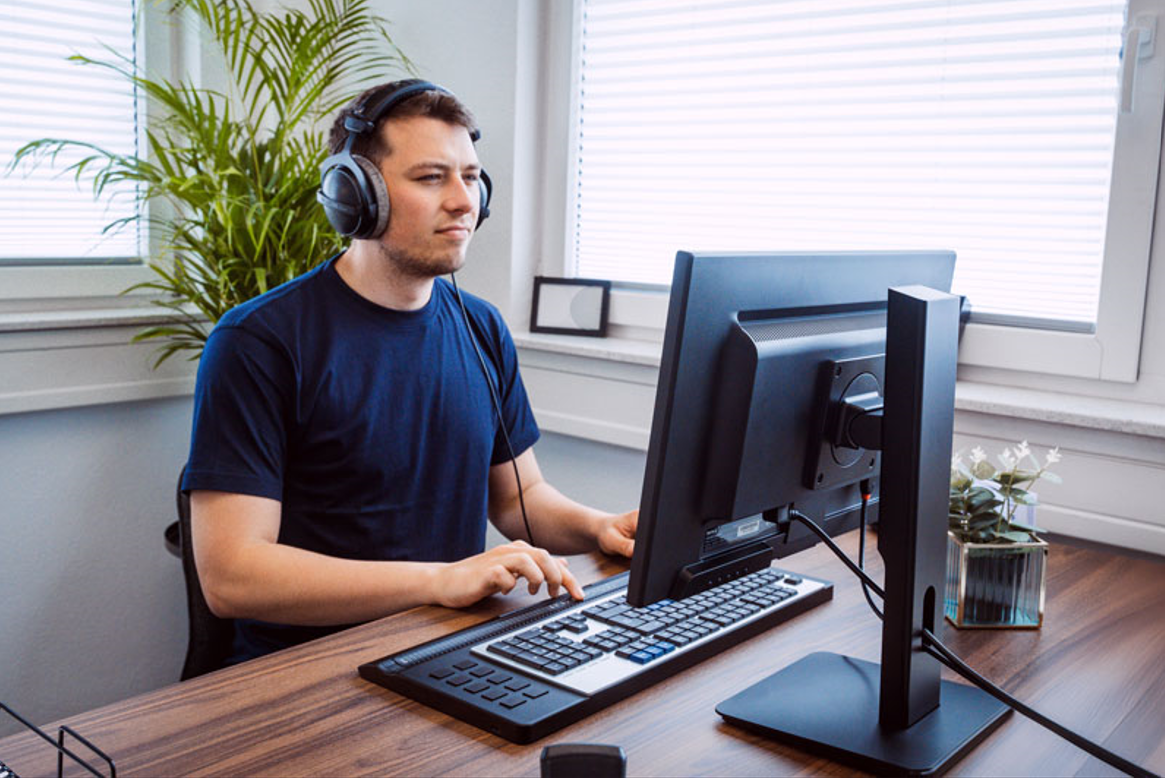 ung mann med headset på kontor jobber med en  slank sort leselist activator pro med integrert QWERTY tastatur.foto
